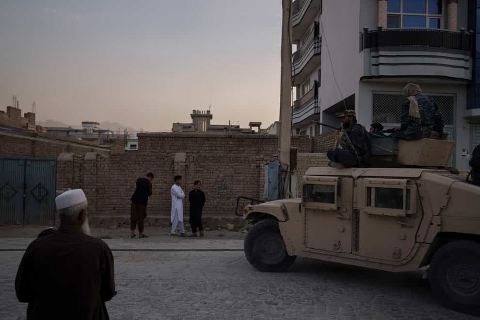 Afghans watch as Taliban fighters ride atop a humvee after detaining four men who got involved in a street fight in Kabul, Afghanistan (AP)
