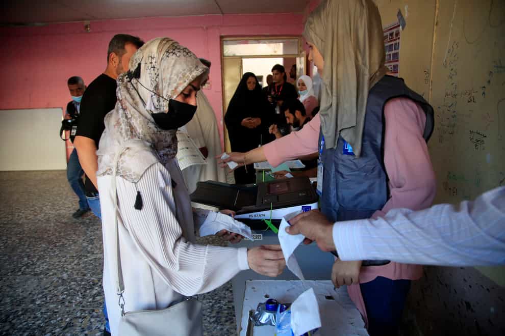 Iraqis queue to cast their votes at a polling station in the country’s parliamentary elections in Baghdad (Hadi Mizban/AP)