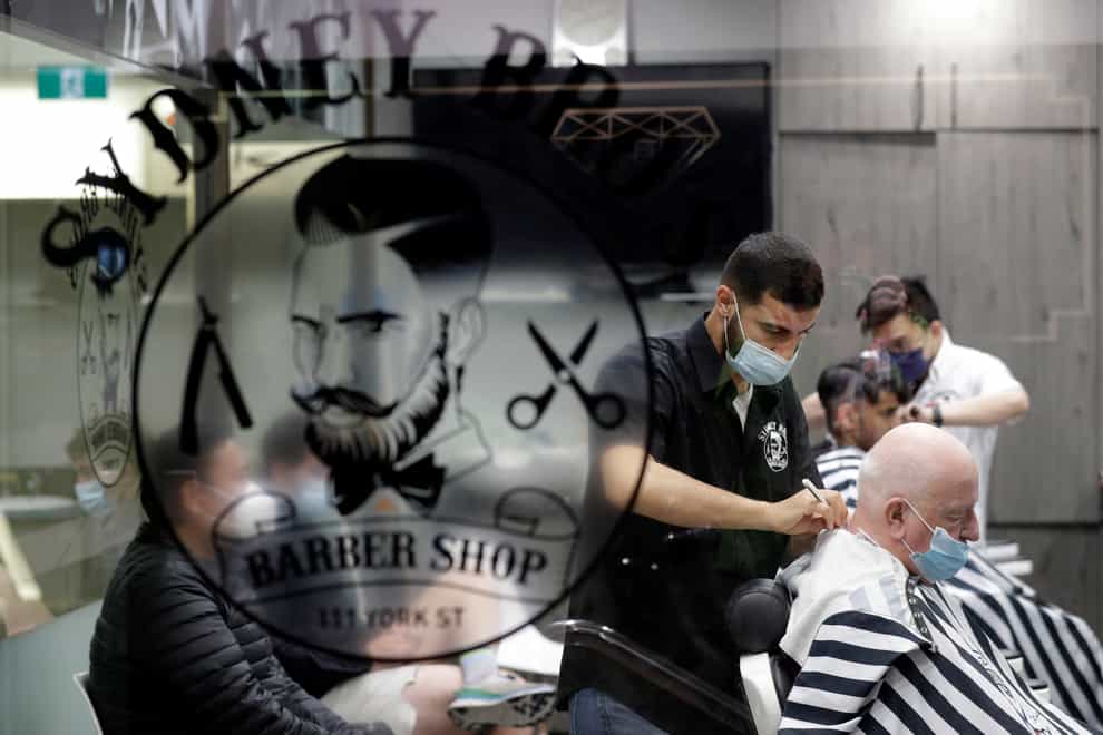 A Sydney barber shop clips and snips some of their first costumers in months after more than 100 days of lockdown on Monday (Rick Rycroft/AP)