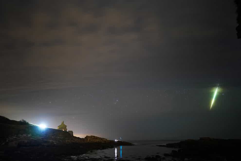 A fisherman watches a meteor during the Draconid meteor shower over Howick rocks in Northumberland ((Owen Humphreys/PA)