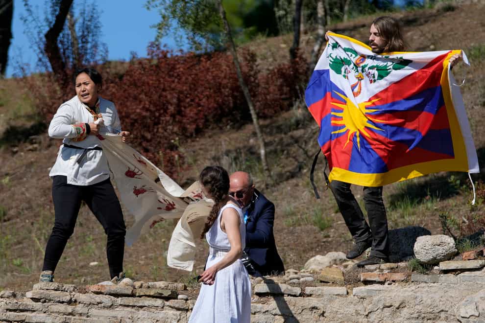 A police officer tries to stop protesters displaying a Tibetan flag and a banner reading “No genocide games” during the lighting of the Olympic flame at Ancient Olympia site, birthplace of the ancient Olympics in southwestern Greece (Thanassis Stavrakis/AP)