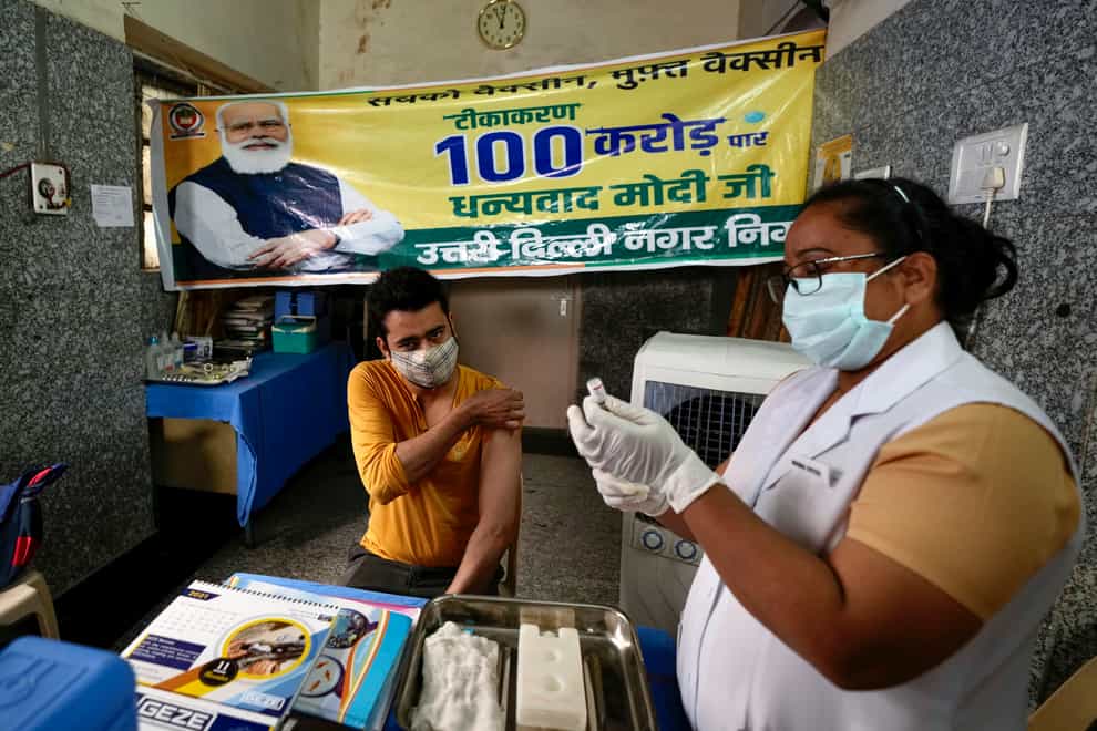 A health worker prepares to give a Covid jab next to a banner thanking Prime Minister Narendra Modi for one billion doses of the vaccine (Manish Swarup/AP)