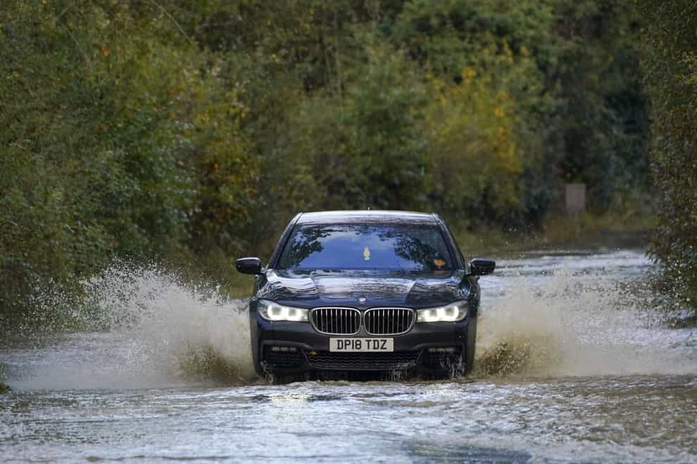 A car drives through flood water on a road in Lingfield, Surrey, after southern England was hit overnight by heavy rain and strong winds (Steve Parsons/PA)