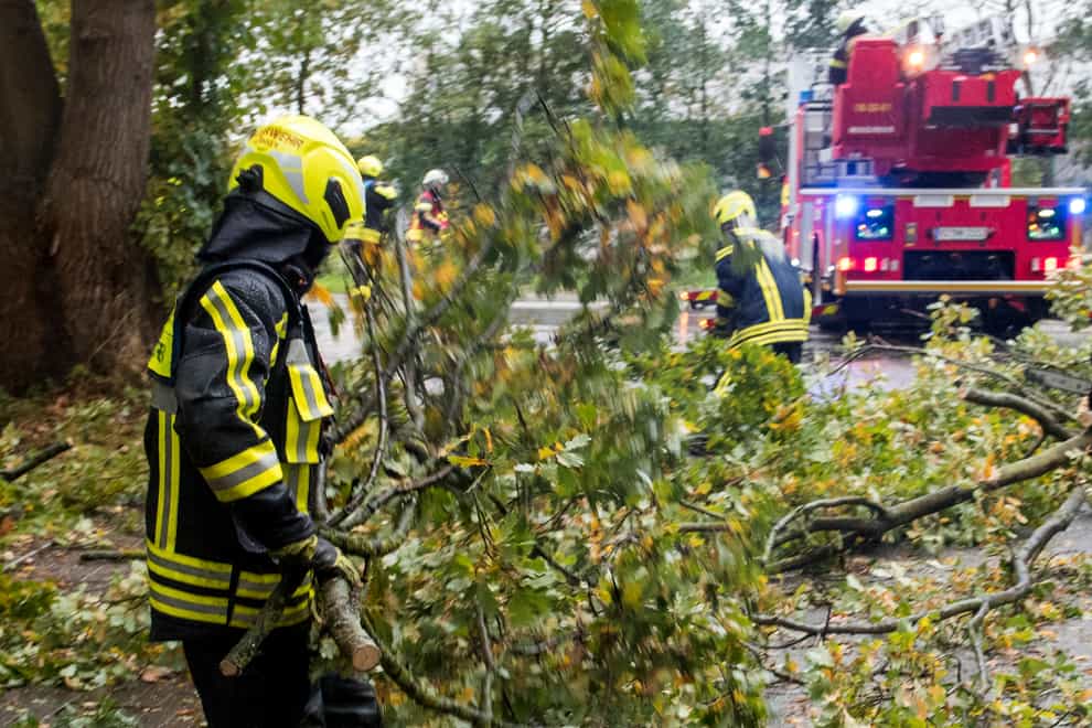 A firefighter removes fallen trees from a road in Hamburg, Germany (Daniel Bockwoldt/dpa via AP)