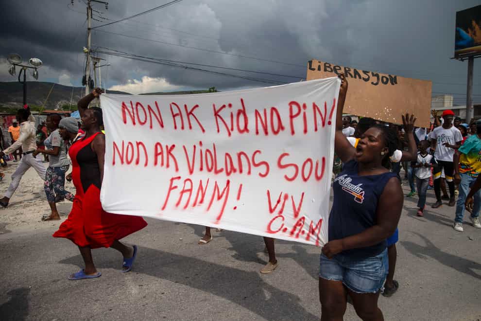 People protest carrying a banner with a message that reads in Creole: ‘No to kidnappings, no to violence against women! Long live Christian Aid Ministries’ (Joseph Odelyn/AP)