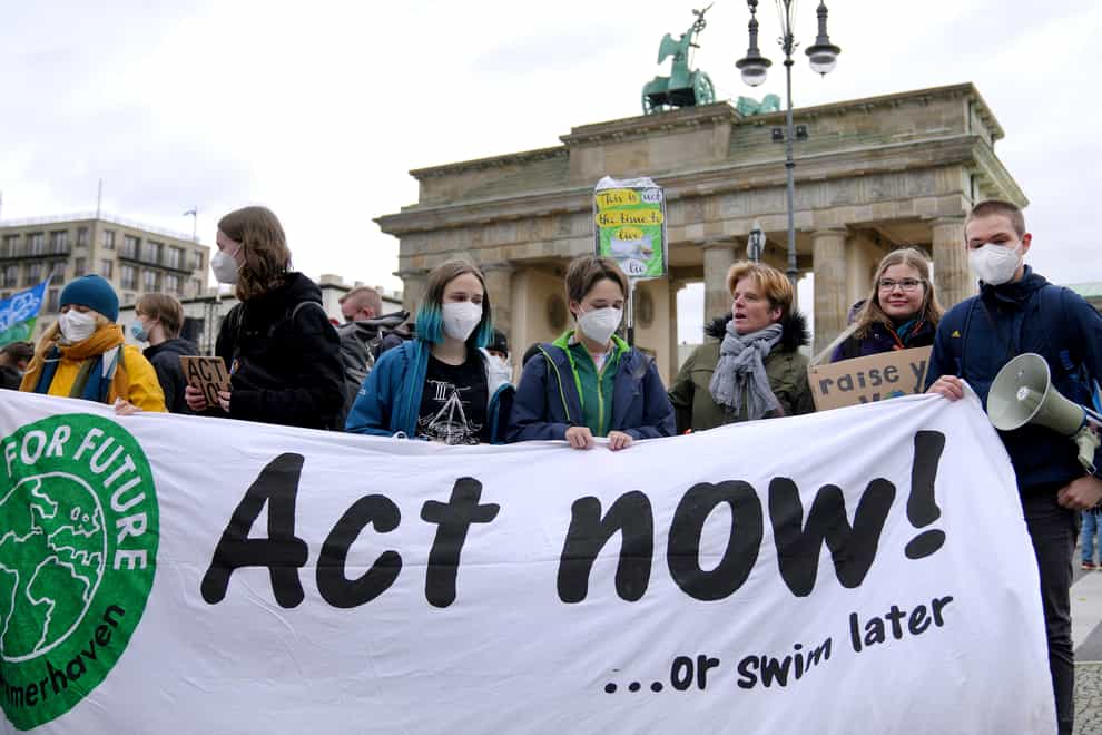 People stand in front of the Brandenburg Gate as they take part in a Fridays For Future climate protest rally in Berlin (Michael Sohn/AP)