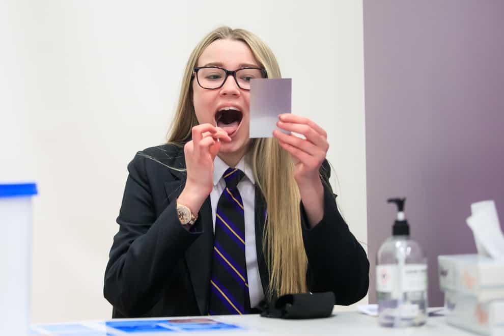 Erin Horn looking in a mirror while taking a Lateral Flow Test as children arrive at Outwood Academy in Woodlands, Doncaster (PA)