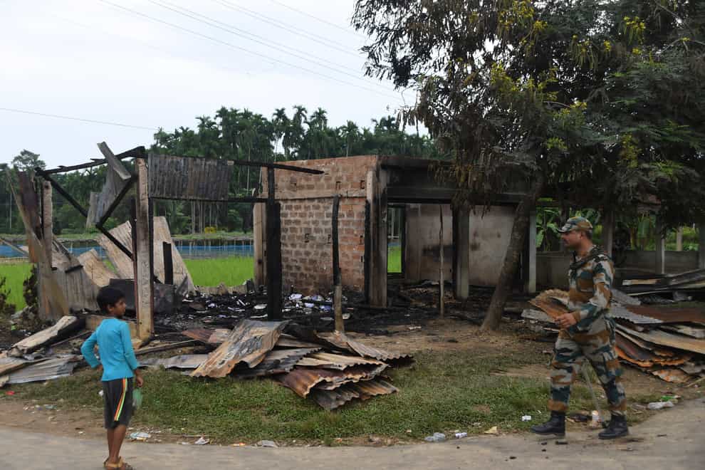 A paramilitary soldier patrols past a shop that was set on fire in Rowa village, about 135 miles from Agartala, in the northeastern Indian state of Tripura (Panna Ghosh/AP)