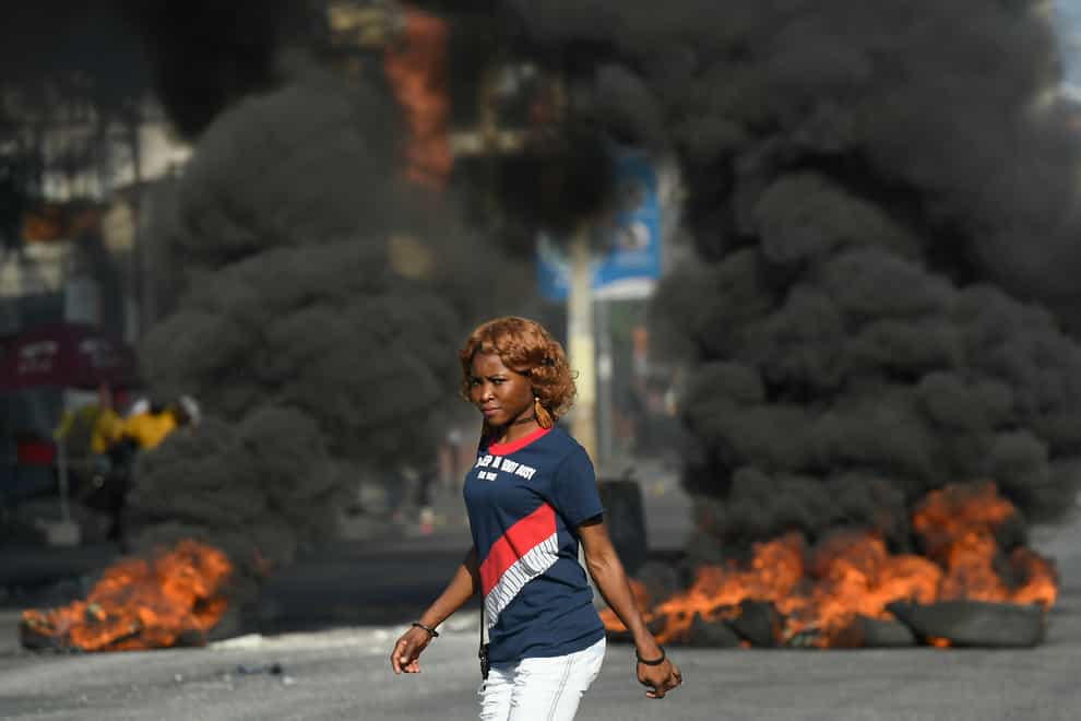 A pedestrian passes a burning roadblock set by anti-government protesters in Port-au-Prince, Haiti (Matias Delacroix/AP)