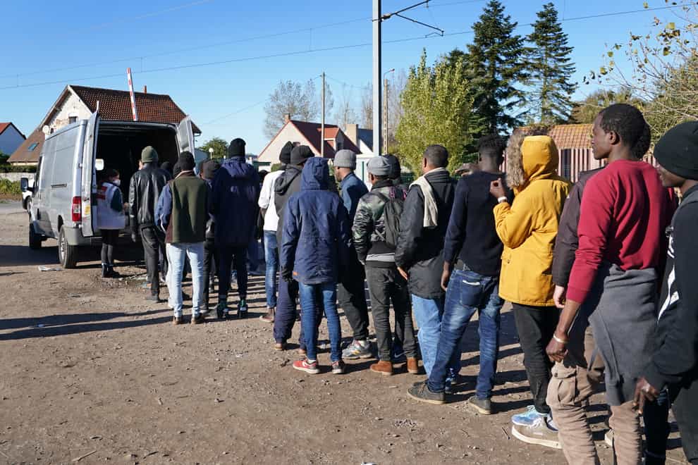 Migrants queue for food at a makeshift camp in Calais (Gareth Fuller/PA)