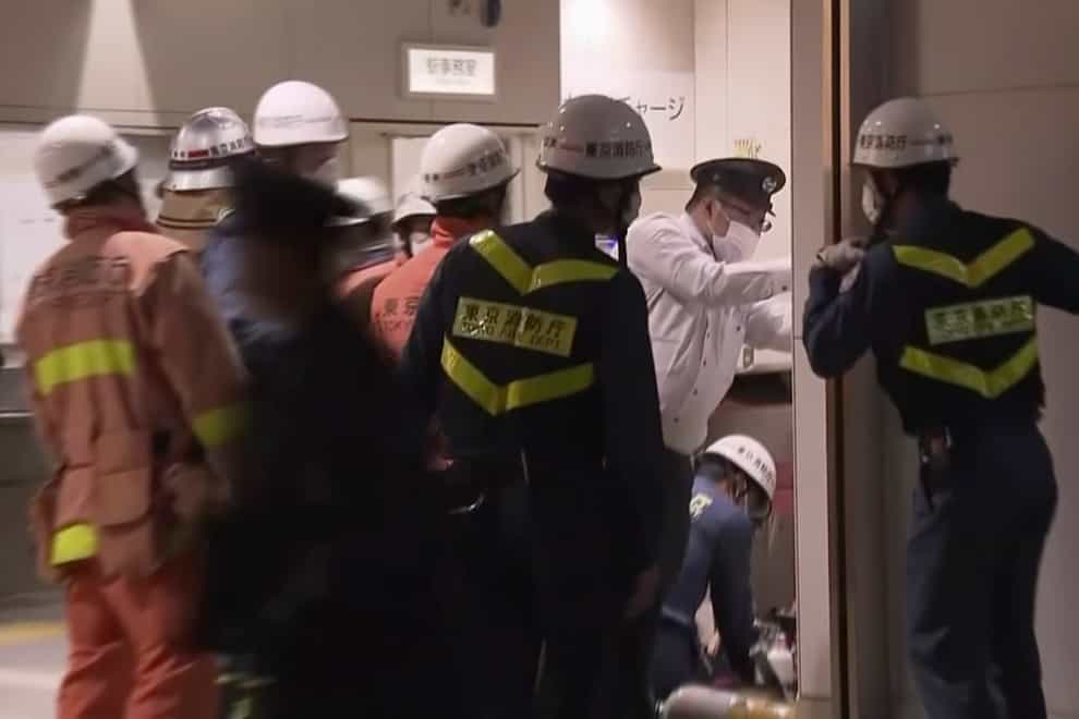 Emergency workers and police investigate the scene at a railway station in Tokyo (NTV/AP)