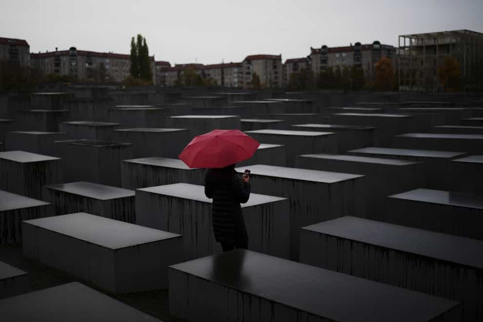A woman with a red umbrella visits the memorial for the murdered Jews of Europe in central Berlin, Germany (Markus Schreiber/AP)