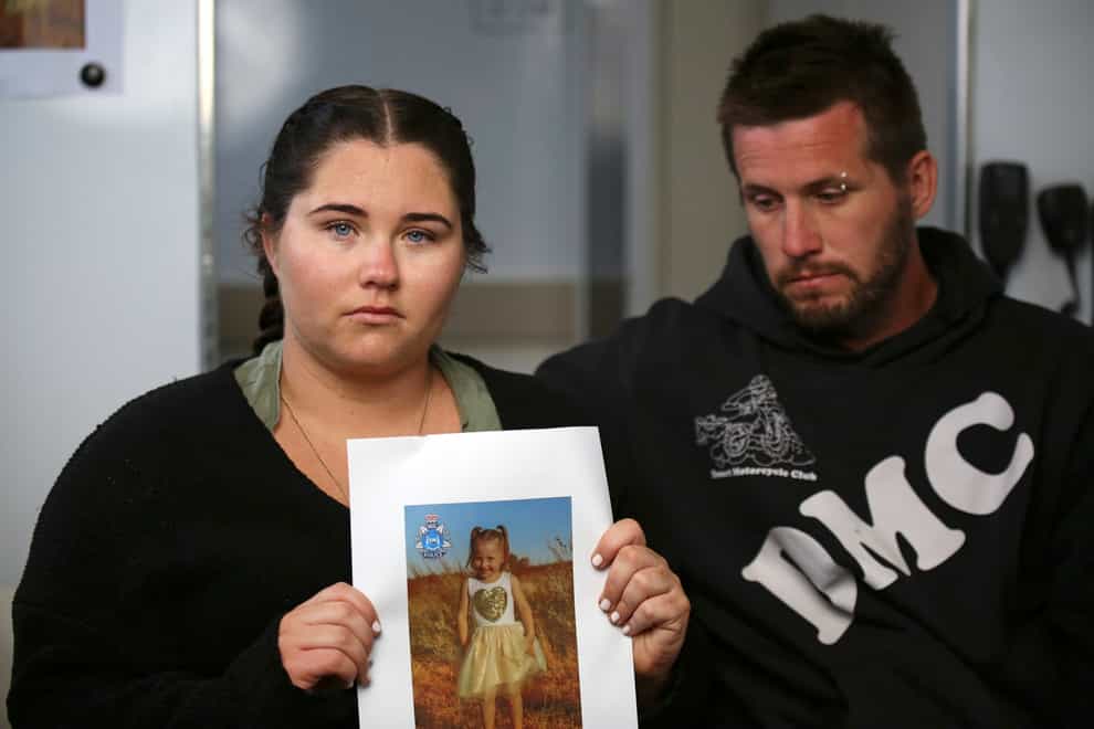 Ellie Smith, left, and her partner Jake Gliddon display a photo of Cleo after she went missing in Western Australia state (James Carmody/AAP Image/Pool via AP)