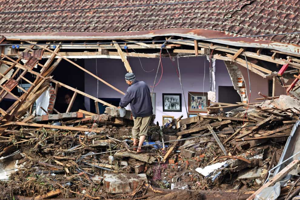 A man inspects the damage to a house following a flash flood in Bulukerto village, Batu, East Java, Indonesia (AP)