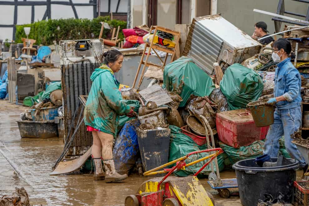 People clean their homes in Bad Neuenahr-Ahrweiler, Germany, after floods in July (Michael Probst/AP)