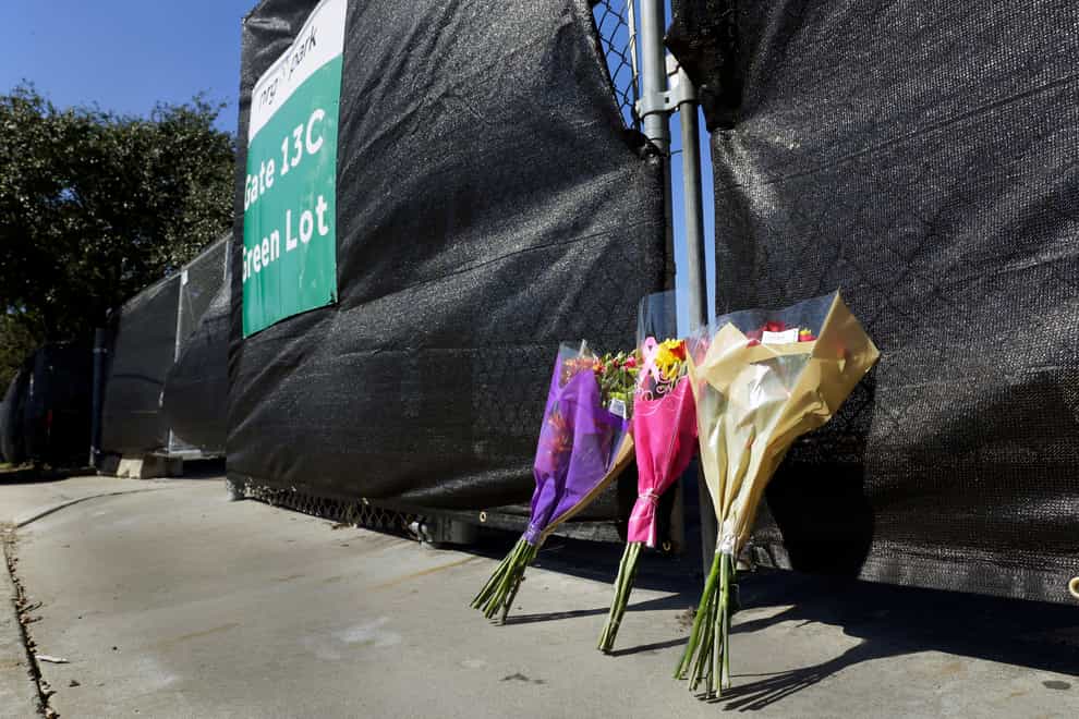 Flowers lie against the south fence surrounding the Astroworld festival grounds the day after several people died and scores were injured during a concert by rapper Travis Scott at the two-day event, held at NRG Park Saturday, Nov. 6, 2021, in Houston. (AP Photo/Michael Wyke)