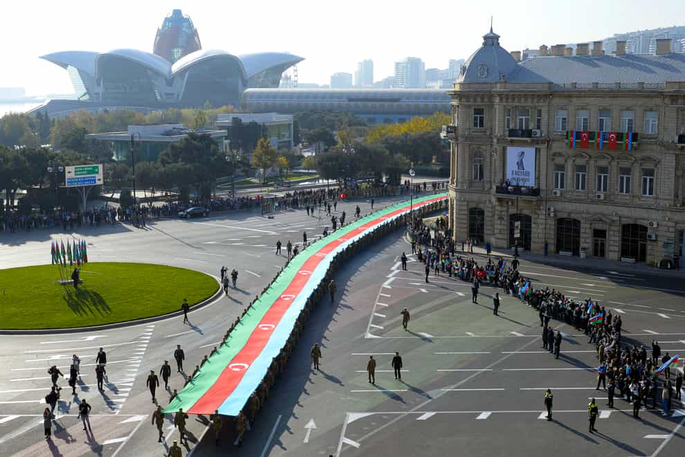 Soldiers carry a giant Azerbaijan national flag to celebrate the Victory Day, in Baku, Azerbaijan (AP)