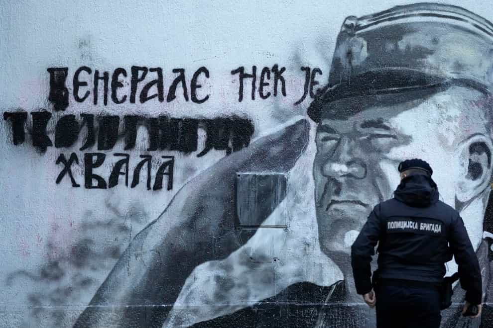 A police officer walks by a mural of former Bosnian Serb military chief Ratko Mladic in Belgrade, Serbia (Darko Vojinovic/AP)