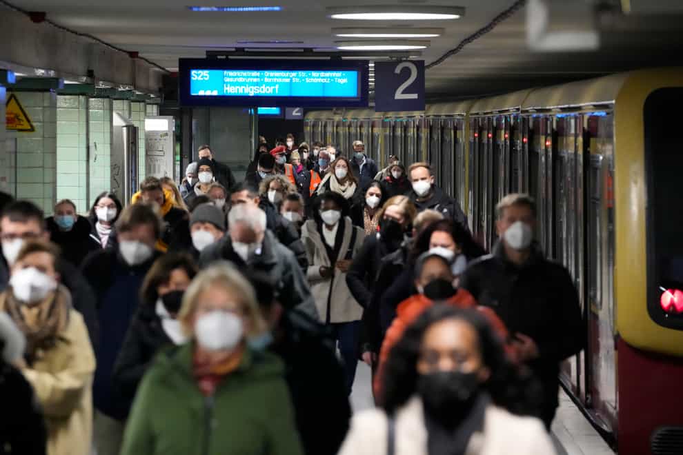 Commuters wearing face masks to protect against the coronavirus as they arrives at the public transport station Brandenburger Tor in central Berlin, Germany, Friday, Nov. 12, 2021. Germany battles a fourth wave of the coronavirus with high number of infections in the recent days. (AP Photo/Markus Schreiber)