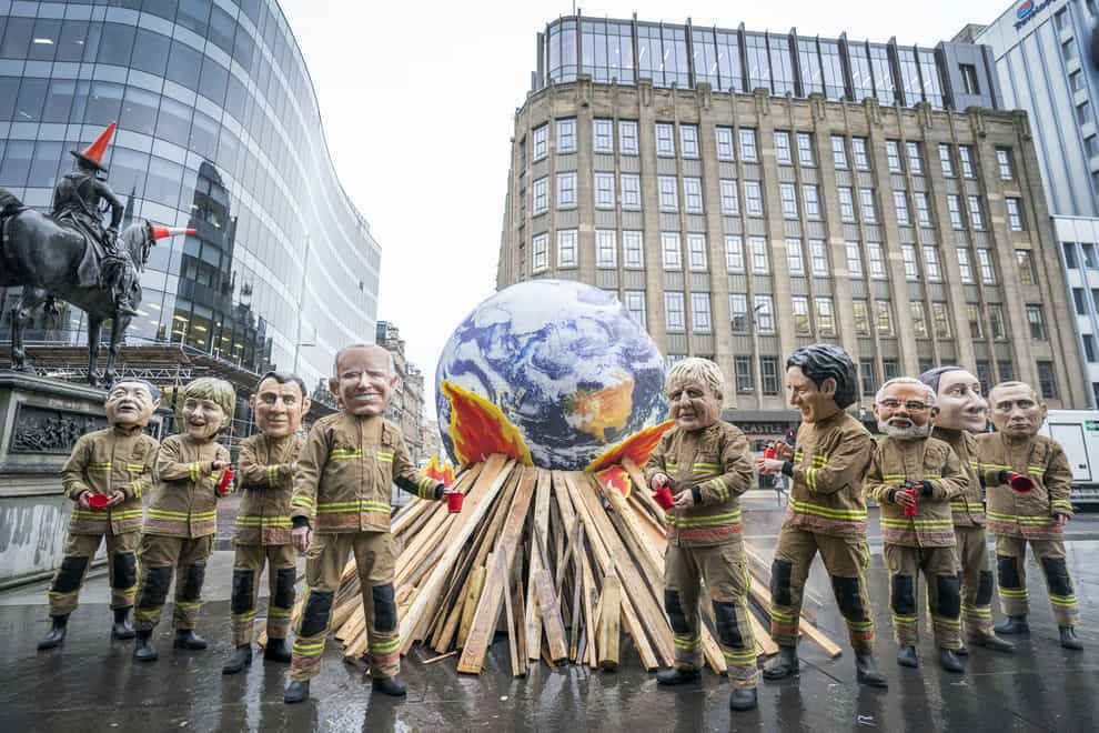 Campaigners wearing ‘big heads’ of world leaders during the final official day of Cop26 (Jane Barlow/PA)
