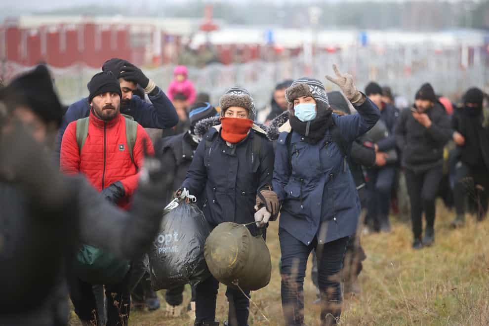 Migrants walk along the barbed wire as they gather at the Belarus-Poland border (Leonid Shcheglov/BelTA pool photo via AP)