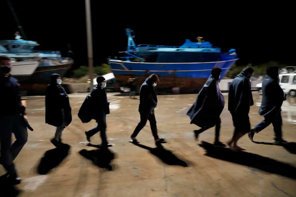 Migrants walk on the quay after disembarking in Roccella Jonica, southern Italy (Alessandra Tarantino/AP