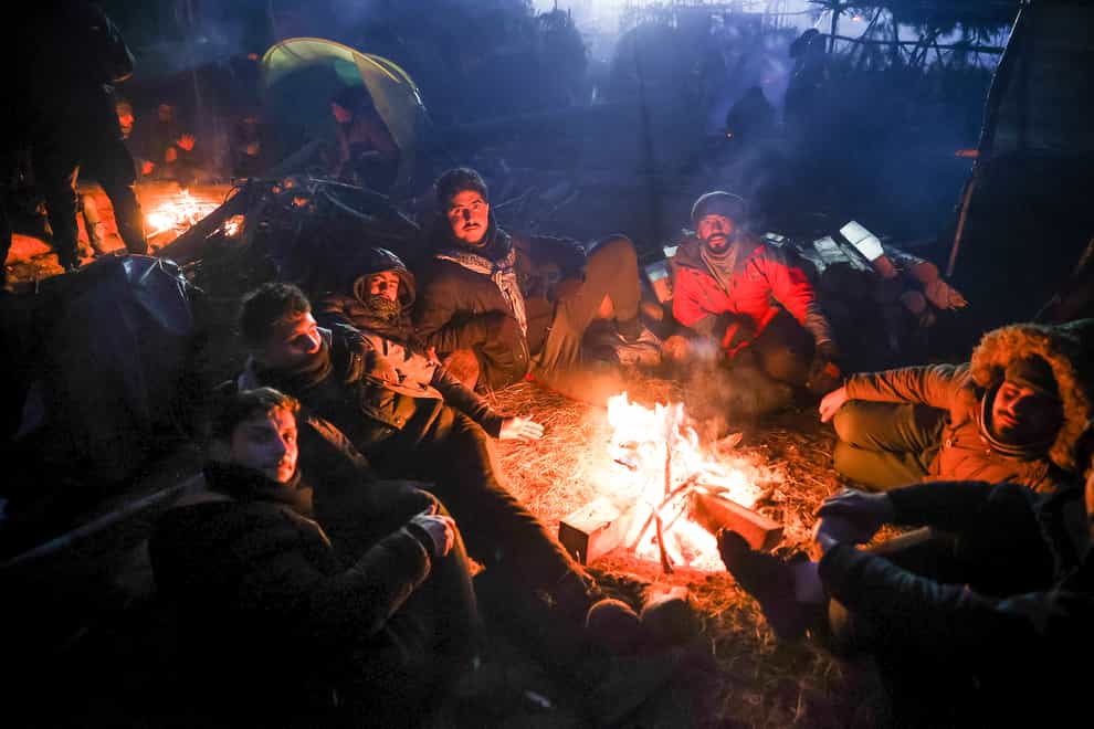 Migrants warm themselves near fire gathering at the Belarus-Poland border near Grodno (BelTA pool photo via AP)