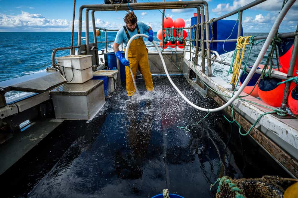 Fisherman Jack Bailey, 25, washes down the deck after a day’s fishing aboard his boat, White Waters, off the coast of Jersey (Ben Birchall/PA)