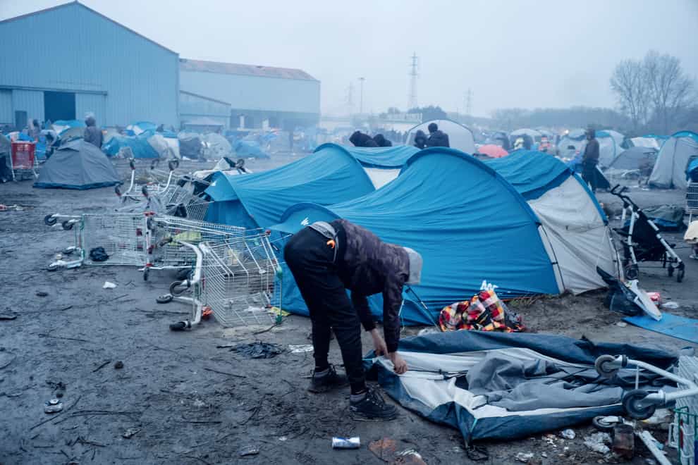 A migrant packs his belongings in a camp in Grande-Synthe, Northern France, Tuesday, Nov. 16, 2021. French police were evacuating migrants from a makeshift camp near Dunkirk, in northern France, where at least 1,500 people gathered in hopes of making it across the English Channel to Britain. Migrants, including some families with young children, could be seen packing their few belongings as police were encircling the camp, on the site of a former industrial complex in Grande-Synthe, east of Dunkirk. (AP Photo/Louis Witter)