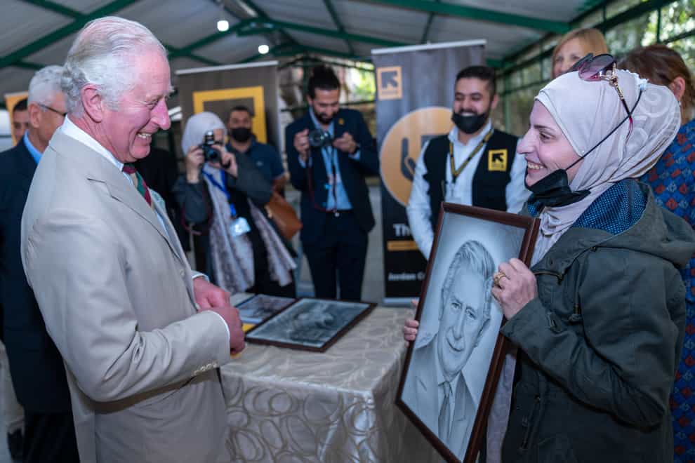The Prince of Wales admires his portrait given to him by the Syrian refugee artist Faihaa, 38, during a visit to the Al Nuzha Community Centre in Jordan, on the second day of the Royal tour of the Middle East (Arthur Edwards/The Sun/PA)