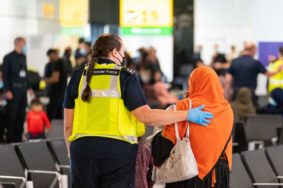A member of Border Force staff assists a female evacuee as refugees arrive from Afghanistan at Heathrow Airport, London in August. (Dominic Lipinski/PA)