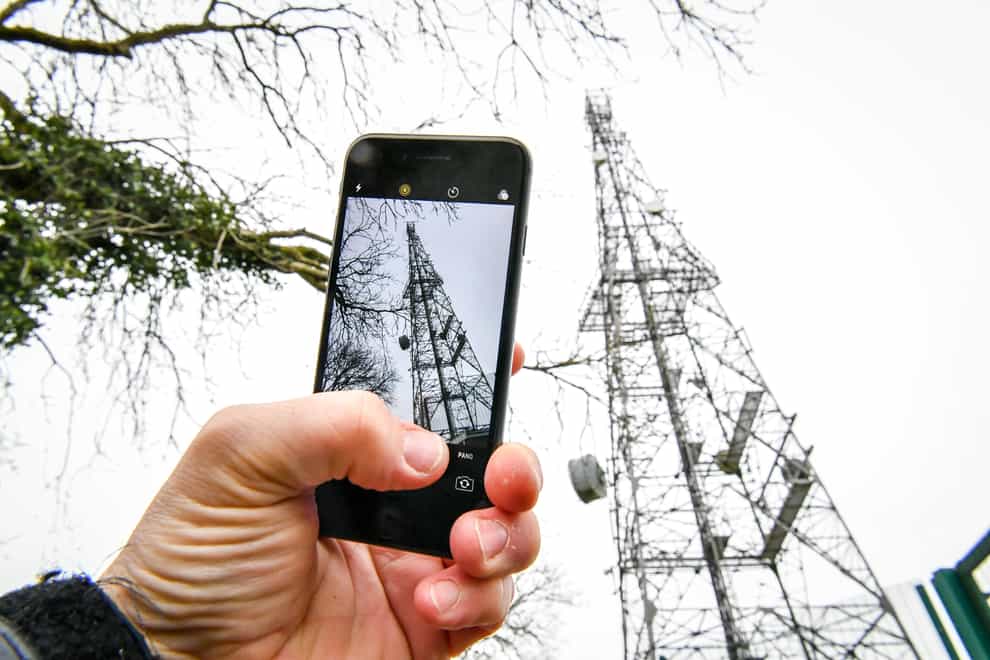 A mobile phone next to a telecoms mast (Ben Birchall/PA)