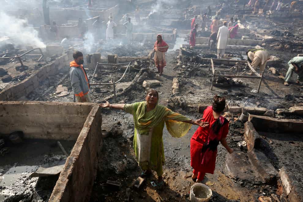 A woman grieves while she and others collect their belongings from the ashes (Fareed Khan/AP)