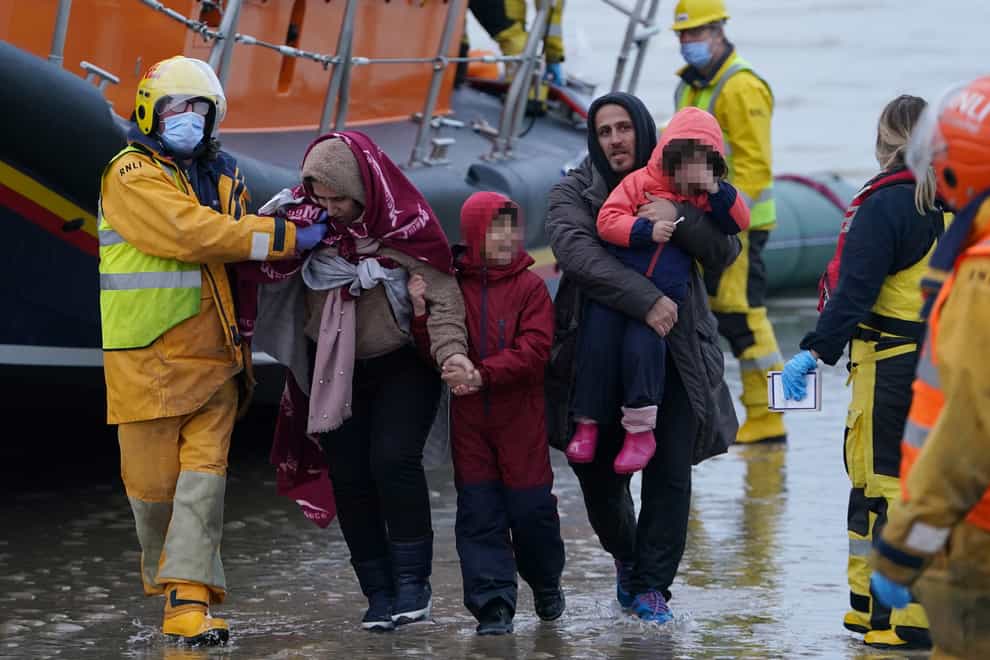 A family is helped to shore as a group of people thought to be migrants are brought in to Dungeness, Kent, by the RNLI (Gareth Fuller/PA)