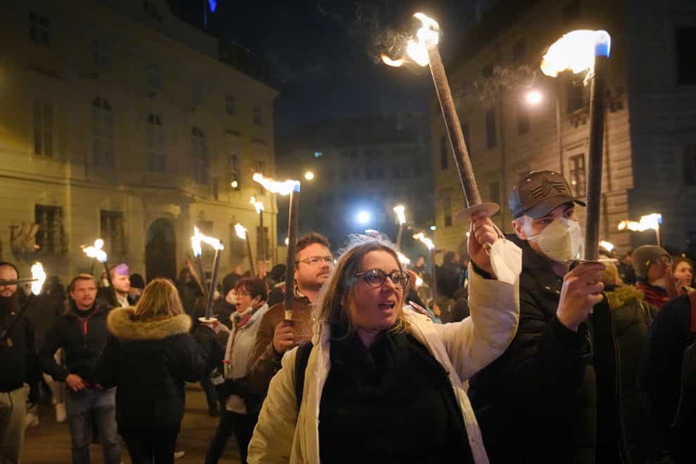 Anti-lockdown protesters hold torches and banners in Vienna (Vadim Ghirda/AP)