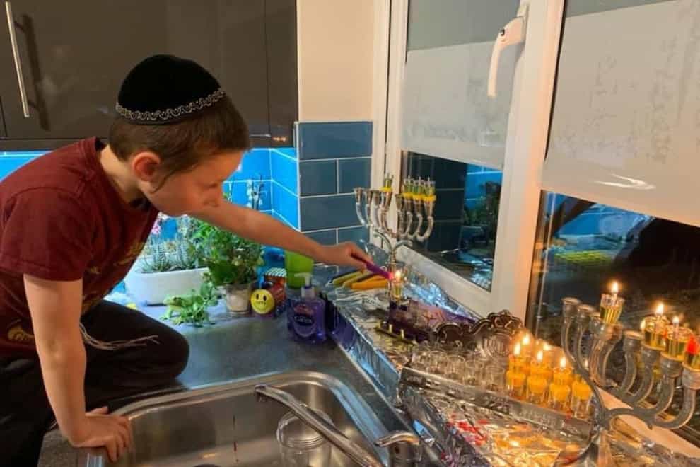 A boy lights a menorah during Hanukkah (Rabbi Elchonon Feldman/PA)