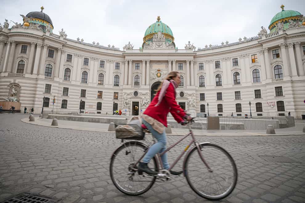 A woman rides a bicycle along an empty street in Vienna in Austria (Vadim Ghirda/AP)