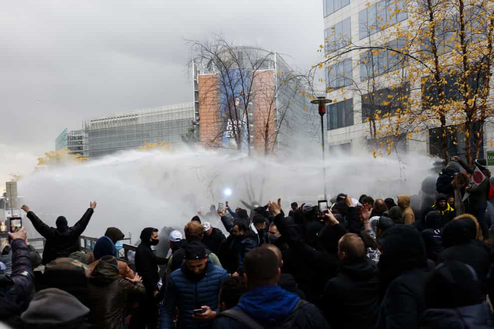 Riot police use a water canon against protestors in Brussels on Sunday (Olivier Matthys/AP)