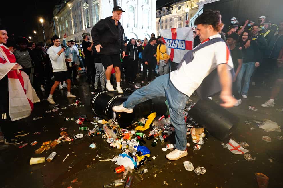 English fans kick and stand on a litter bin in Piccadilly Circus (Victoria Jones/PA)