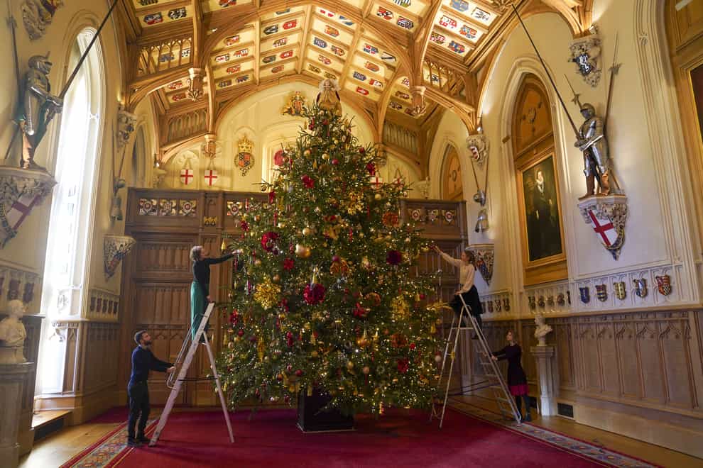 Members of the Royal Collection Trust staff put the finishing touches to a Christmas tree in St George’s Hall (Steve Parsons/PA)
