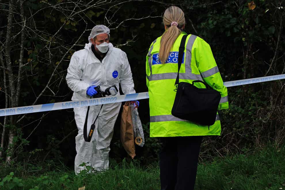 A crime scene investigator searches woodland near Thurlestone Walk (Ben Birchall/PA)