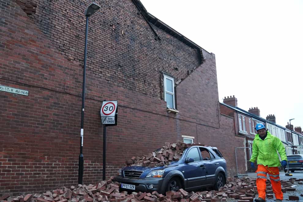 A man makes safe fallen masonry from a property, which has damaged a car in Roker, Sunderland (Owen Humphreys/PA)