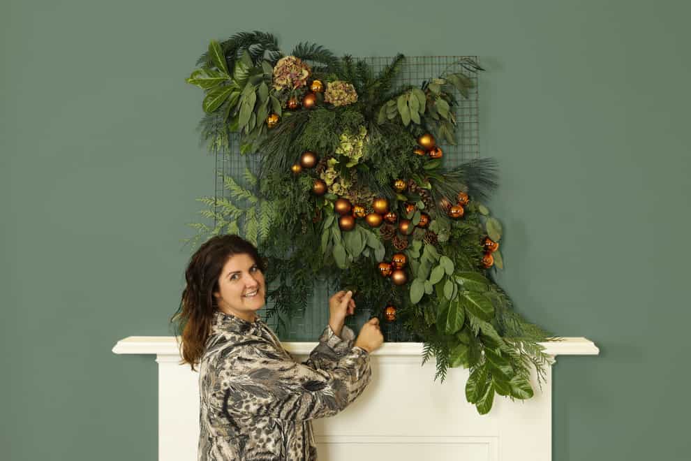 Dobbies’ stylist Rebecca Stanton with a festive floral tapestry (Dobbies Garden Centres/PA)