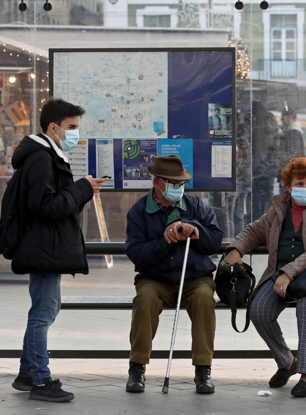 People wearing face masks to curb the spread of Covid-19 sit at a bus stop in Lisbon, Portugal (Ana Brigida/AP)