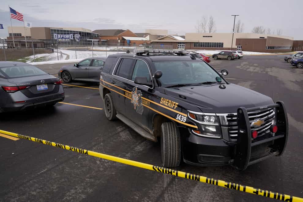 An Oakland County Sheriff’s deputy guards the parking lot of Oxford High School in Oxford, Mich., Wednesday, Dec. 1, 2021. A 15-year-old sophomore opened fire at the school, killing several students and wounding multiple other people, including a teacher. (AP Photo/Paul Sancya)