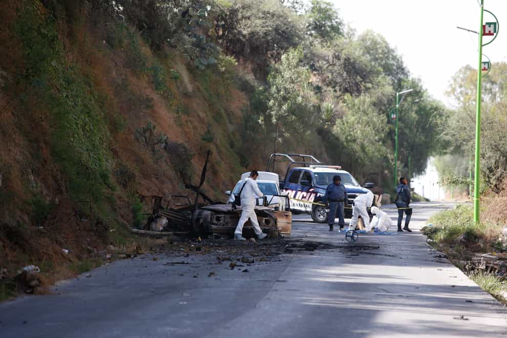 Forensic investigators work an area where a burned-out car was found after a gang rammed several vehicles into a prison and escaped with nine inmates, in Tula, Mexico, Wednesday, Dec. 1, 2021. Local media reported that the burned-out cars found in the city of Tula after the attack were car bombs. Authorities said they were investigating how the vehicles caught fire. (AP Photo/Ginnette Riquelme)