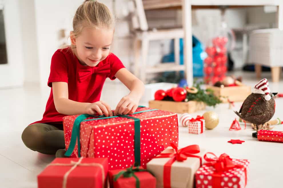 Child unwrapping a Christmas present (Alamy/PA)