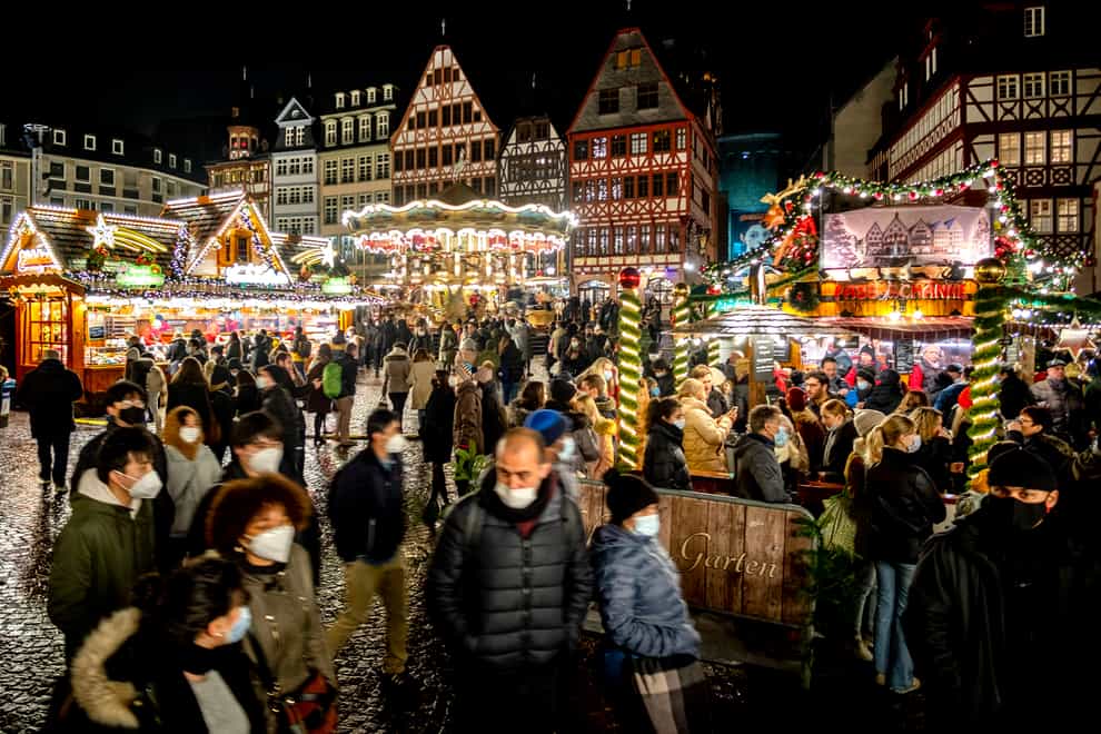 People wear face masks as they visit the traditional Christmas market in Frankfurt, Germany (Michael Probst/AP)