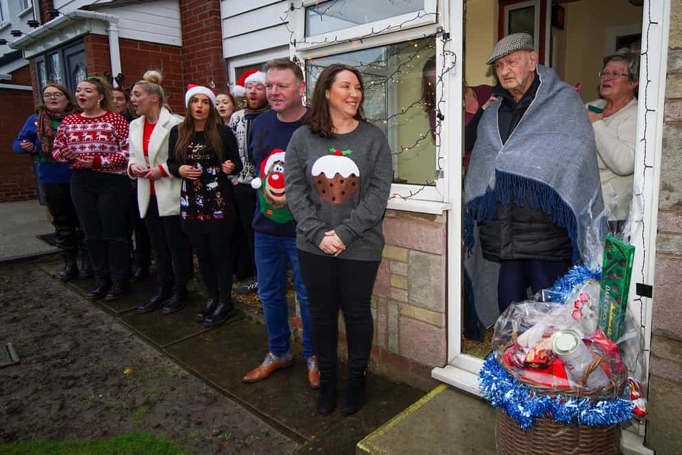 Lottery winners Sharon and Nigel Mather, who won a £12.4 million jackpot, deliver a Christmas hamper to 104-year-old war veteran Tom Beevers with the help of the LMA Choir (Peter Byrne/PA)