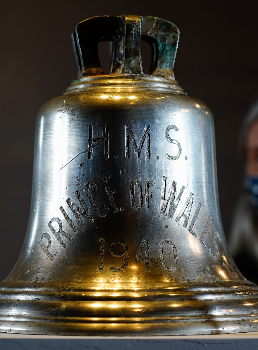 Victoria Ingles, senior curator at the National Museum of the Royal Navy, looks at the ship’s bell from HMS Prince of Wales which was sunk in the Second World War (Andrew Matthews/PA)